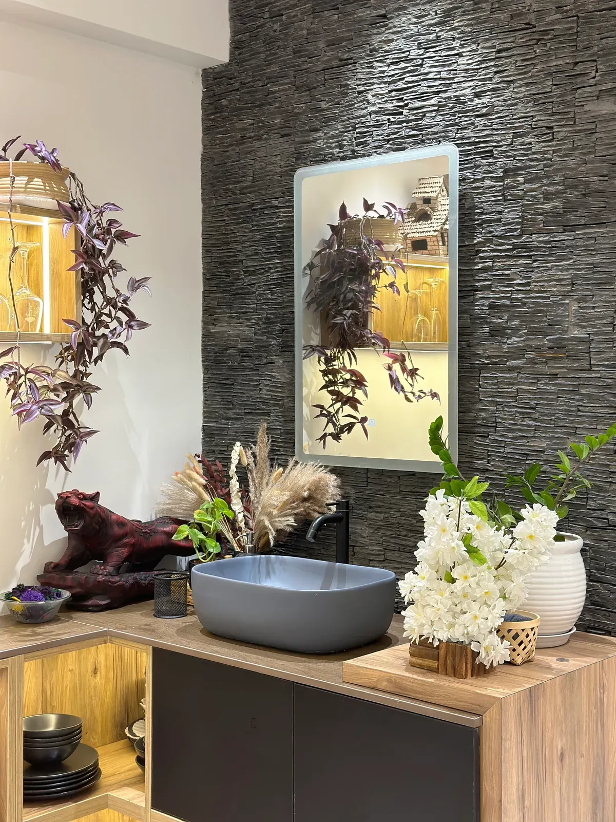 Wash basin counter against a black stone feature wall — The Aakar